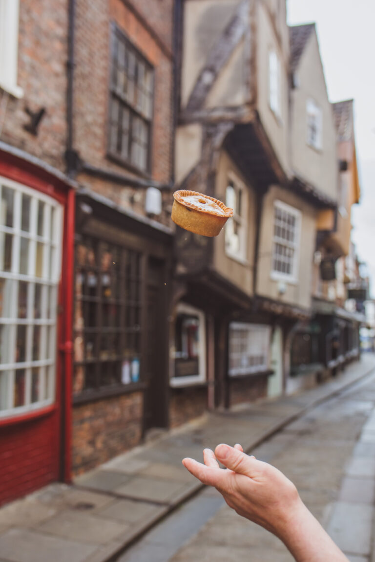A person throwig. apork pie in the air outside the Shambles Sausage and Pie Company